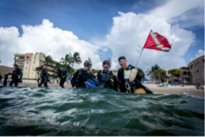 A group of divers smile while standing in the shallow end of the Atlantic