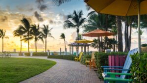 The sun rises over the Atlantic Ocean and lights up the sky like a raindbow over a brick path lined with Adirondack chairs.
