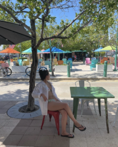 A young woman sits at a cafe table outside a shop in Lauderdale-By-The-Sea.